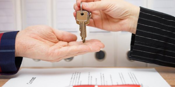 people handing keys to each other with paperwork with the words contract